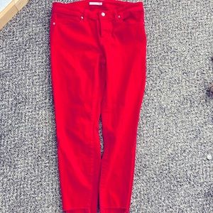 Cherry red capri length pants with distressed details at the ankles